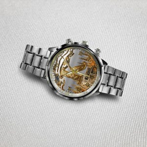 May include: A silver wristwatch with a detailed face featuring gold accents and Roman numerals. The watch has a silver band and two small dials on the side. The watch face has the name "Kevin" on it.