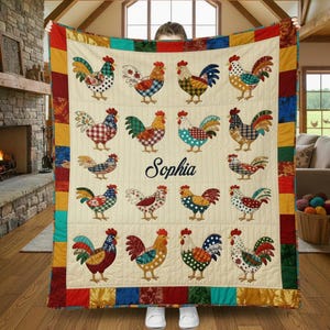 Op de afbeelding: Een crèmekleurige quilt met een herhaald patroon van kleurrijke haanillustraties. De hanen hebben verschillende patronen en kleuren, waaronder rood, blauw, groen en geel. De naam "Sophia" is in cursiefschrift in het midden geschreven. De quilt heeft een patchwork rand.