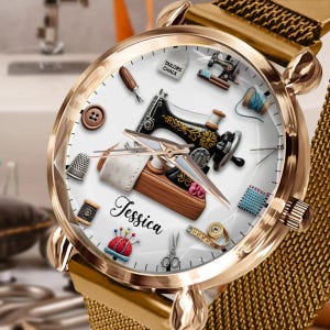 Puede incluir: Reloj dorado con esfera blanca con ilustraciones de costura. La esfera incluye una máquina de coser, dedal, tijeras y el nombre "Jessica". El reloj tiene una correa de malla dorada.