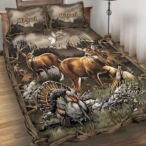 Peut inclure: Ensemble de literie avec une scène de faune représentant des cerfs, une dinde et des oiseaux, sur un fond de camouflage. Les taies d'oreiller affichent le nom "Michael". La palette de couleurs comprend des bruns, des verts et des tons beiges.