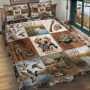 May include: A quilted bedspread and two pillowcases featuring a hunting theme. The design includes images of ducks, a hunting dog, hunting gear, and a shotgun. The color palette is dominated by earth tones, with camouflage accents.