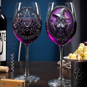 Op de afbeelding: Twee wijnglazen met paarse vloeistof. Eén glas heeft een pentagram- en rozenontwerp, de andere een heksenillustratie met de naam "Sophia". Een zwarte kaars met een pentagram is ook zichtbaar.