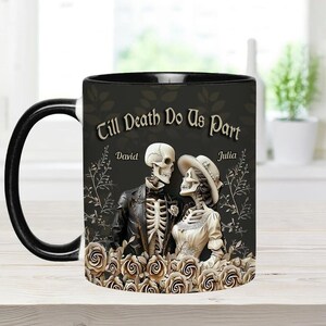 May include: Black ceramic mug with a white interior and handle. The mug features a design with a skeleton couple, roses, and the text "Till Death Do Us Part" with the names "David" and "Julia".