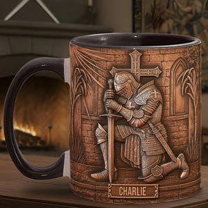 May include: A brown ceramic mug featuring a detailed relief of a kneeling knight in full armor, holding a sword before a cross. The mug has a black handle and interior, with the name "CHARLIE" at the base.
