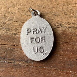 K&ouml;nnte beinhalten: Silberner ovaler Anh&auml;nger mit den Worten "Pray For Us" und "Italy" eingraviert.
