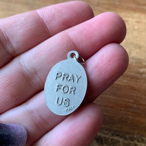 K&ouml;nnte beinhalten: Silberner ovaler Anh&auml;nger mit den Worten "Pray for Us" und "Italy" auf der R&uuml;ckseite.