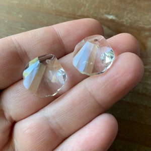 May include: Two clear crystal teardrop shaped beads with a hole at the top for stringing. The beads have a faceted design.