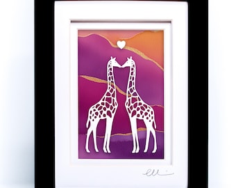 May include: A framed artwork featuring two white giraffe silhouettes facing each other with a small white heart above them. The background is a gradient of purple, pink, and orange with gold glitter accents. The frame is black with a white mat.