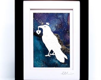 May include: A framed art print featuring a white silhouette of a crow wearing a small crown and holding a heart-shaped padlock in its beak. The background is a deep blue and purple nebula-like wash with gold flecks, set in a black frame.