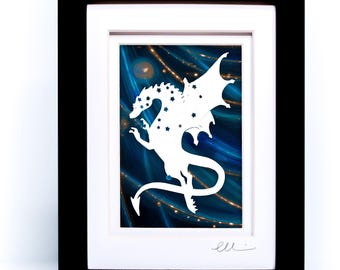 May include: A framed artwork featuring a white silhouette of a dragon adorned with star-shaped cutouts, set against a deep blue background with swirling light patterns. The piece is encased in a black frame with a white mat and a signature at the bottom.