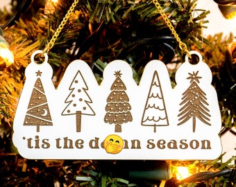May include: White wooden Christmas ornament with five stylized trees and the text 'tis the darn season'.
