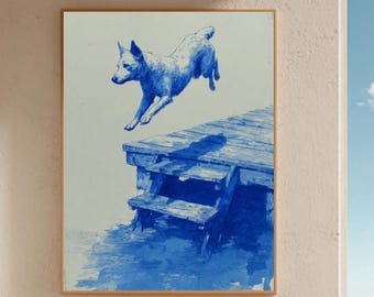 Puede incluir: Una obra de arte enmarcada en azul y blanco representa a un perro saltando de un muelle de madera. La obra cuelga de una pared beige sobre una silla de mimbre con un cojín azul. La escena da a una playa y al océano bajo un cielo azul.