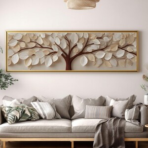 Könnte beinhalten: Gerahmtes Wandbild mit einem Baumdesign mit braunen Ästen und cremefarbenen Blättern. Das Kunstwerk ist vor einem beigen Hintergrund platziert und goldfarben gerahmt. Das Kunstwerk hängt über einem grauen Sofa.