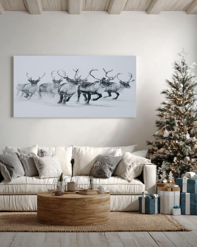 May include: A monochrome print of reindeer in motion adorns the wall above a cream sofa. A decorated Christmas tree with fairy lights and presents is to the right. A round wooden coffee table sits on a jute rug, creating a festive living room scene.