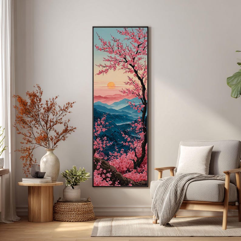 May include: Vertical framed art print showing a Japanese landscape with a cherry blossom tree in full bloom. The artwork features a sunset over blue mountains and a light blue sky, with pink blossoms.