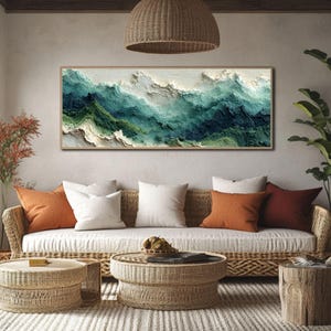 以下が含まれることがあります： ティール、緑、白の色合いで海の波を描いた額入りの抽象芸術作品。織り込まれたソファの上には、オレンジと白のクッションが置かれています。織り込まれたコーヒーテーブルとサイドテーブルがリビングルームを完成させています。