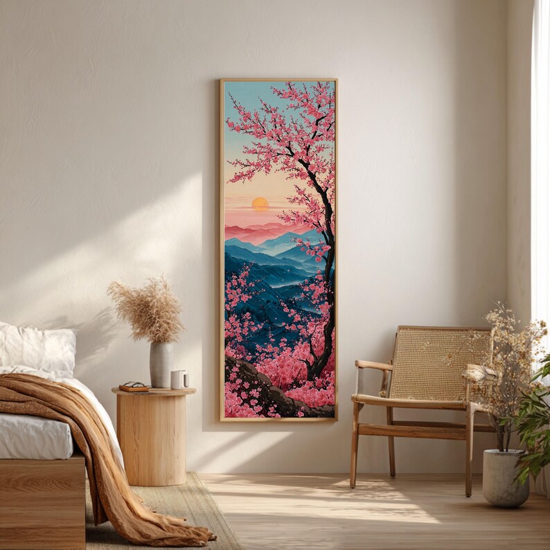 May include: A framed vertical art print showing a tranquil landscape. A cherry blossom tree with pink flowers is on the right, with blue mountains, a setting sun, and a light blue sky. The artwork is in a gold frame.