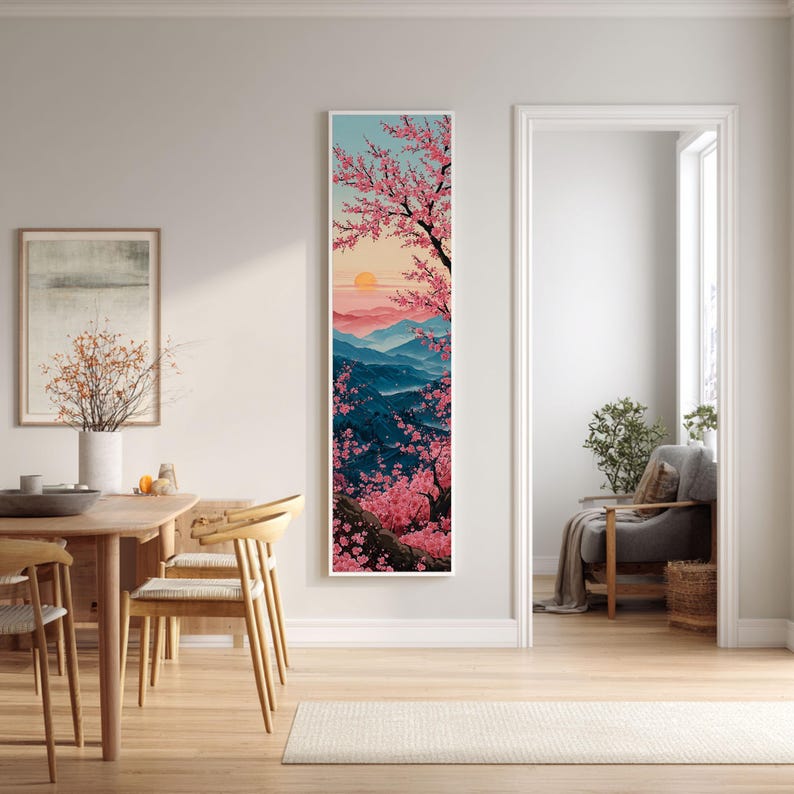 May include: A long, framed art print depicting a Japanese scene with pink cherry blossom trees, a setting sun, and blue mountains. The artwork is displayed in a bright, modern interior.