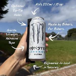 Könnte beinhalten: Ein schwarzer Halter zur sicheren Aufnahme einer 500 ml Monster Energy Ultra Dose. Die Dose ist weiß mit schwarzen Grafiken und dem Text "MONSTER ENERGY ULTRA". Der Halter hat "Optionale Kabelbinderlöcher" und "Gorilla Strength Klebeband". Der Text "Made by Bikers, for Bikers" ist ebenfalls sichtbar.