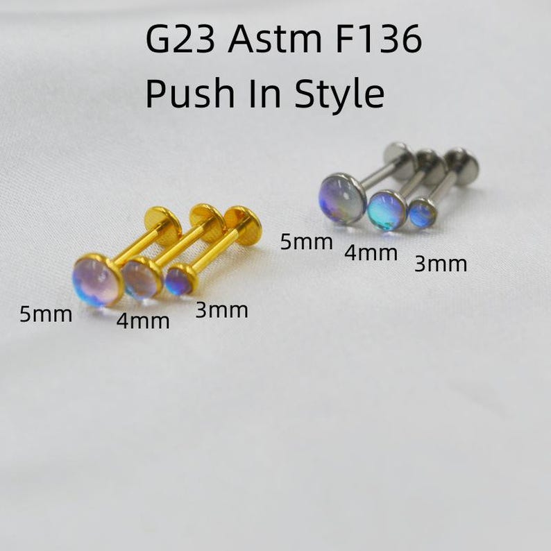 May include: G23 Astm F136 Push In Style labret studs in gold and silver tones. Each stud features a round iridescent stone top. The set includes sizes 3mm, 4mm, and 5mm for both color variations, clearly labeled with text next to each piece.