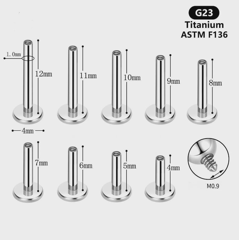 Op de afbeelding: Een set van negen zilverkleurige G23 Titanium ASTM F136 labretstaafjes met platte ronde voetjes. De staafjes vari&euml;ren in lengte van 4 mm tot 12 mm, met een dikte van 1,0 mm en een voetdiameter van 4 mm. Een inzetstuk toont het M0.9 schroefdraad.