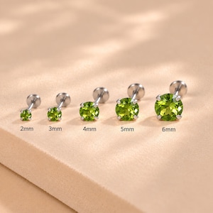May include: Five silver-toned stud earrings with round, faceted green peridot-colored stones in prong settings. The studs are arranged in a row, labeled with sizes 2mm, 3mm, 4mm, 5mm, and 6mm, showing a gradual increase in stone diameter.