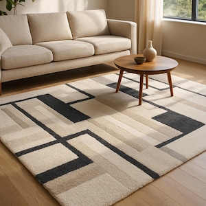 Può includere: Un divano beige e un tavolino rotondo in legno poggiano su un tappeto a motivi geometrici. Il tappeto presenta un design di rettangoli e linee neri, beige e grigi. Un vaso bianco e una piccola ciotola marrone sono sul tavolo.