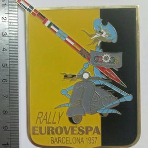 Peut inclure: Épinglette vintage avec un design de scooter Vespa sur fond jaune et noir. L'épinglette porte l'inscription "RALLY EUROVESPA BARCELONA 1957" et un mât avec des drapeaux. L'épinglette mesure environ 10 cm de haut.