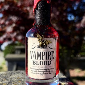 Può includere: Una bottiglia di vetro piena di liquido rosso, etichettata "VAMPIRE BLOOD". Il collo della bottiglia è avvolto con una corda nera e sigillato con cera rossa. Un ciondolo a forma di pipistrello pende dal collo. Un oggetto unico a tema Halloween.