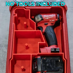 Peut inclure: Mallette à outils rouge avec compartiments, contenant une perceuse électrique rouge et noire et une batterie noire. Le texte "NO TOOLS INCLUDED" est visible en haut. La perceuse est marquée "Milwaukee FUEL".