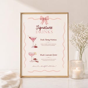 May include: A framed sign titled Signature Drinks with a pink bow illustration. It lists a Pink Cherry Martini and a Blush Lemonade Spritz with watercolour cocktail illustrations, ingredients, and the text cheers to a beautiful celebration!
