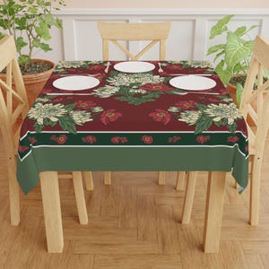 May include: A rectangular tablecloth featuring a deep maroon background with a floral pattern of white chrysanthemums and red flowers. The border includes a dark green stripe with small red floral accents and a solid light green bottom edge.