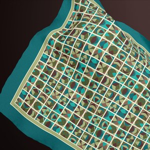 May include: A teal square scarf with a geometric pattern of squares, circles, and semi-circles in shades of teal, brown, and olive green. The scarf has a light green border and a dark teal edge.