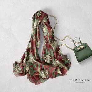 May include: A maroon scarf featuring a repeating floral pattern in cream and green with vertical stripes, paired with a small olive green handbag that has a gold-tone metal chain strap and a gold-tone clasp. The text SEACLAIRE copyright 2026 is visible.