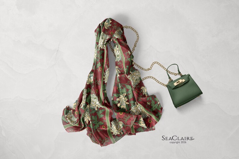 May include: A maroon scarf featuring a repeating floral pattern in cream and green with vertical stripes, paired with a small olive green handbag that has a gold-tone metal chain strap and a gold-tone clasp. The text SEACLAIRE copyright 2026 is visible.