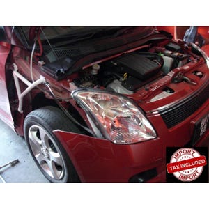 May include: A red car with the hood open, revealing the engine bay and a white metal fender brace installed near the front wheel. The vehicle features a clear headlight assembly, a black grille, and a silver alloy wheel with a multi-spoke design.