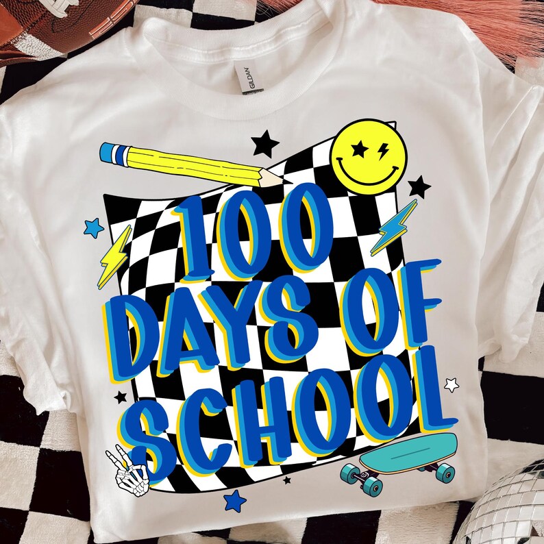 May include: White t-shirt with a colorful graphic celebrating 100 days of school. The design includes a checkered flag, a yellow pencil, a smiley face, stars, lightning bolts, a peace sign, and a skateboard. The text reads "100 DAYS OF SCHOOL".