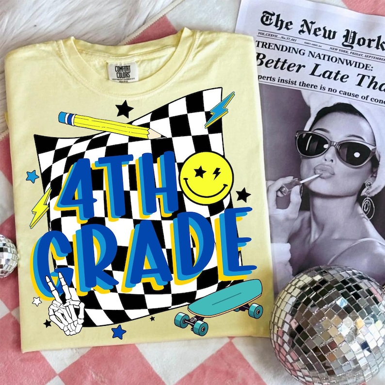 May include: A light yellow Comfort Colors t-shirt with a graphic design for 4th grade. The design includes a checkered flag, a smiley face, a pencil, stars, a skateboard, and the words "4TH GRADE" in blue and yellow.