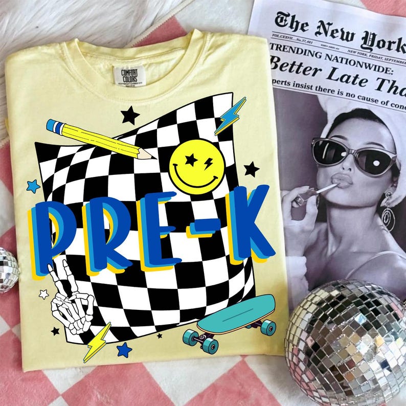 May include: Yellow Comfort Colors t-shirt with a graphic design featuring a checkered flag, a smiley face, a pencil, stars, lightning bolts, a skateboard, and the word "PRE-K" in blue and yellow.
