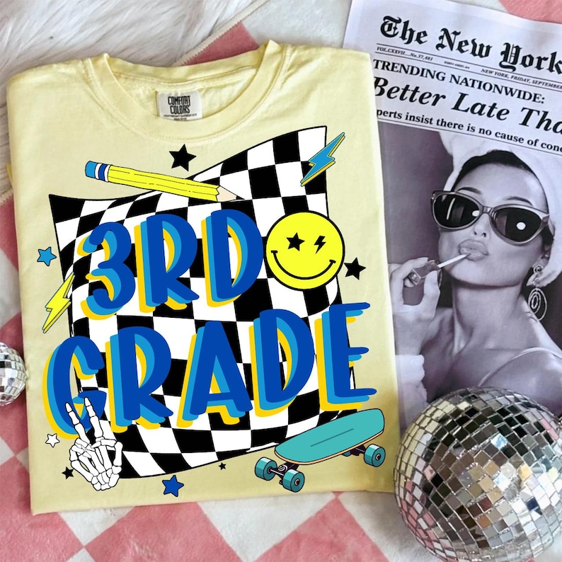 May include: A light yellow t-shirt with the words "3RD GRADE" in blue and yellow, a checkered flag design, a smiley face, a pencil, a skateboard, and a peace sign. A newspaper and a disco ball are in the background.