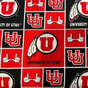 May include: A red and black fabric with a repeating pattern of the University of Utah logo, a stylized 'U' inside a circle, and the words 'University of Utah'.