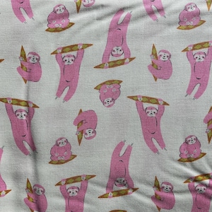 May include: A fabric pattern featuring pink sloths in various poses, including upside down, sitting, and holding a brown surfboard. The sloths are set against a light beige background. The design is repeated across the fabric.