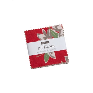 May include: A red fabric square with a white floral pattern and green leaves. The fabric has a Moda Fabrics label with the text "At Home by Bonnie & Camille".