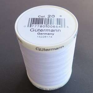 May include: A white spool of Gütermann sewing thread. The label reads "Col. 20" and "Germany." The thread is 100% polyester. The spool is cylindrical and has a white label with black text and a barcode.