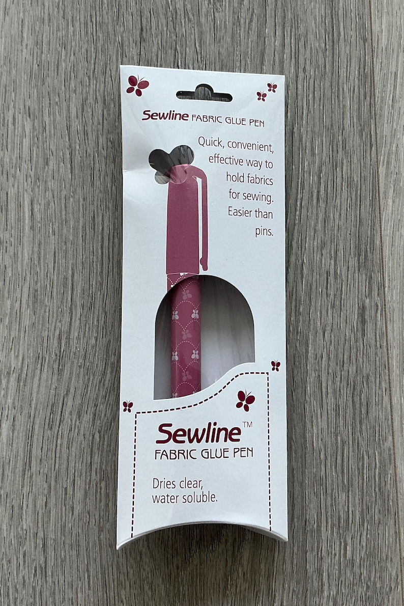 May include: A pink fabric glue pen with a butterfly design on the packaging. The packaging says "Sewline Fabric Glue Pen" and "Dries clear, water soluble".