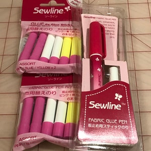 May include: Sewline Fabric Glue Pen and 6 glue stick refills. The glue pen is pink with a butterfly design. The glue sticks are pink, blue, and yellow. The packaging is pink and white with Japanese text.