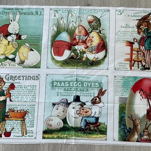 May include: A white fabric panel featuring vintage Easter-themed illustrations. The panel includes images of rabbits, decorated eggs, and text such as "Paas Egg Dyes" and "Easter Greetings". The fabric is printed with a variety of colors.