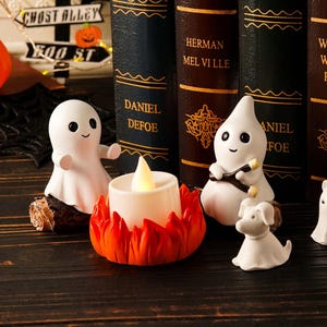 May include: Halloween decorations with white ghost figurines, a dog figurine, and a candle with an orange flame design. The background includes antique books and a sign that reads "Ghost Alley Boo St."