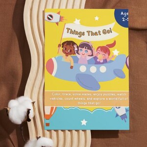 May include: A children's activity book titled "Things That Go!" features illustrations of children in a blue airplane. The cover is yellow with a blue border and includes text about coloring, tracing, and solving puzzles. The age range is 2-5.