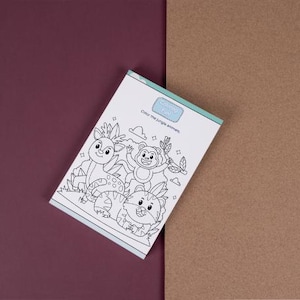 Puede incluir: Un libro para colorear para niños con una cubierta azul y blanca. La portada dice "Coloring Fun" y "Color the jungle animals". El libro muestra dibujos lineales de un ciervo, un mono y un tigre. El fondo está dividido entre burdeos y marrón.
